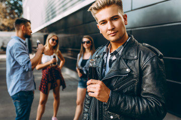 A group of young friends, girls and guys walk together in the city, have fun and drink drinks