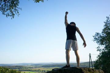 sportsman on a rock rising one arm as a winner