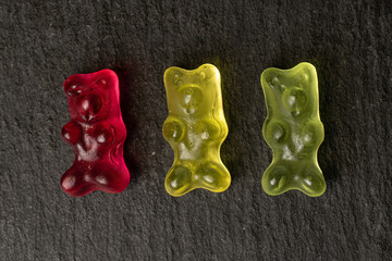 Group of three whole gummy bear flatlay on grey stone