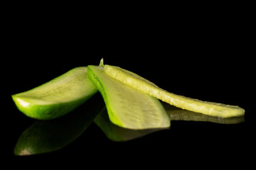 Group of three pieces of mini green cucumber isolated on black glass