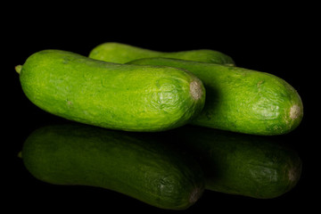 Group of three whole mini green cucumber isolated on black glass