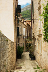 Obraz premium Traditional old and narrow european street. The winding street between the houses of the old city. Plants in pots stand near the brick walls.