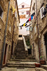Traditional narrow european street between houses. Street with stairs. European courtyard with linen on the rope.
