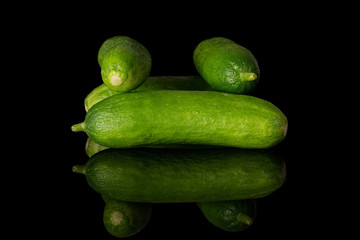 Group of four whole mini green cucumber isolated on black glass