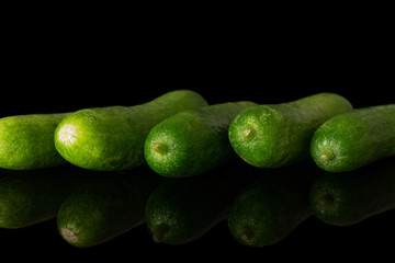 Group of five whole mini green cucumber isolated on black glass