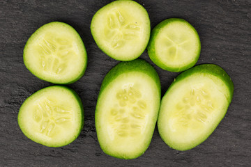 Group of six pieces of mini green cucumber flatlay on grey stone