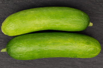 Group of two whole mini green cucumber flatlay on grey stone