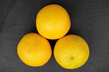 Group of three whole fresh bright orange flatlay on grey stone
