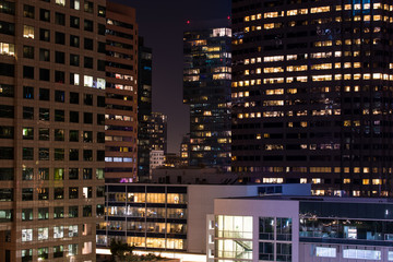 Night scene of a dense cityscape of modern high rise buildings and skyscrapers with glowing windows...