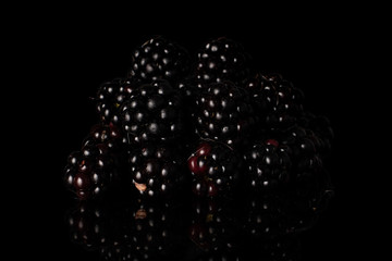 Lot of whole fresh black blackberry heap isolated on black glass
