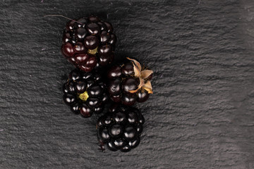 Group of four whole fresh black blackberry flatlay on grey stone