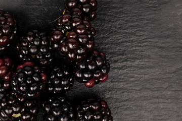 Lot of whole fresh black blackberry flatlay on grey stone