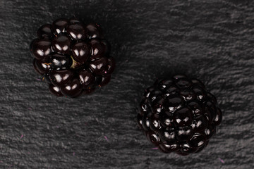 Group of two whole fresh black blackberry flatlay on grey stone