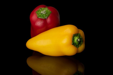 Group of two whole fresh pepper isolated on black glass