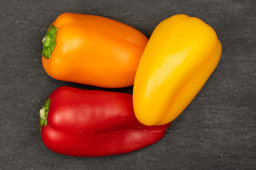 Group of three whole fresh pepper flatlay on grey stone