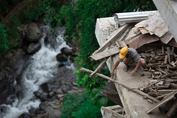 Robotnik budujący dom nad górskim strumieniem w Banaue na Filipinach 