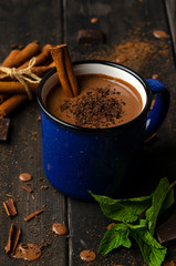 cup of hot chocolate, cinnamon sticks, mint and chocolate on wooden