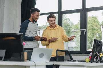 smiling multicultural programmers looking at computer monitor together