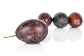 Group of four whole sweet purple plum isolated on white background
