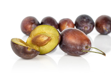 Group of seven whole two halves of sweet purple plum isolated on white background