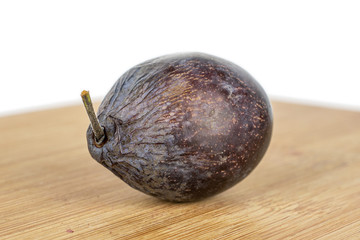 One whole rotten purple plum with bamboo plate isolated on white background