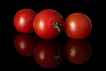 Group of three whole disordered fresh red tomato isolated on black glass