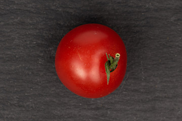 One whole fresh red tomato flatlay on grey stone