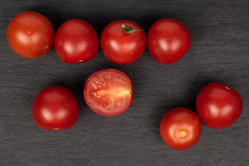 Group of seven whole one half of fresh red tomato flatlay on grey stone