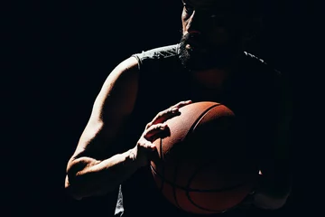 Poster Dramatic portrait of basketball player over dark background © kleberpicui