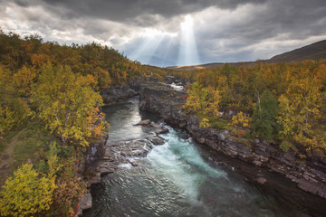 Fototapeta premium Sunny fall autumn view of Abisko National Park, Kiruna Municipality, Lapland, Norrbotten County, Sweden, with Abiskojokk river, road and Nuolja mountain, near border of Finland, Sweden and Norway