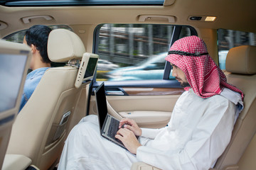 Arabian businessman working with laptop in car