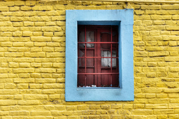Fototapeta na wymiar janela vermelha com parede amarela