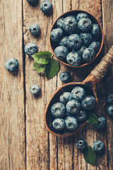 Blueberries in wooden spoon on old wood table. Healthy eating and nutrition concept.