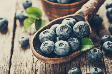 Blueberries in wooden spoon on old wood table. Healthy eating and nutrition concept.