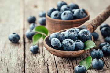 Blueberries in wooden spoon on old wood table. Healthy eating and nutrition concept.
