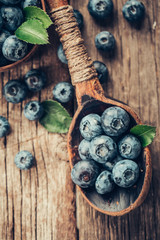 Blueberries in wooden spoon on old wood table. Healthy eating and nutrition concept.