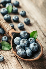 Blueberries in wooden spoon on old wood table. Healthy eating and nutrition concept.