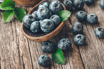Blueberries in wooden spoon on old wood background. Healthy eating and nutrition concept.