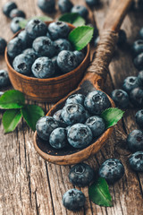 Blueberries in wooden spoon on old wood background. Healthy eating and nutrition concept.