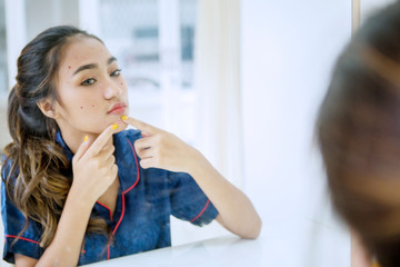 Beautiful teenage girl squeezing pimple on her face