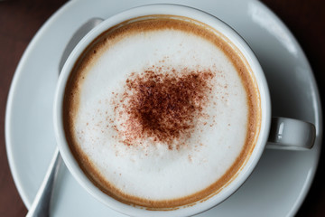 Cappuccino or latte with frothy foam, coffee cup top view closeup.