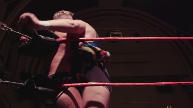 Pro wrestler splashes opponent in corner of ring during wrestling match