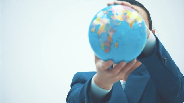 Portrait of a cute and happy female teacher on a white background. During this time, the globe holds on its elongated hands. Close-up.