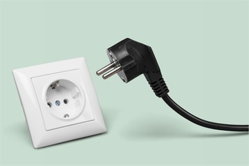 White electrical plug in the electric socket on a wall