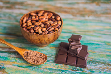 Chocolate and cocoa beans on color wooden background