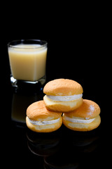 side view cakes with cream filling with cup of soy milk on black background vertical composition