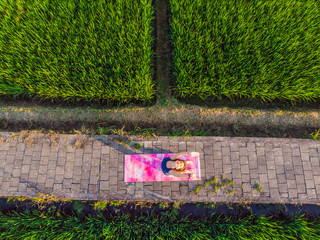 Young woman practice yoga outdoor in rice fields in the morning during wellness retreat in Bali....