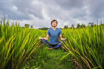 Naklejka na ściany i meble Man doing yoga in a rice field