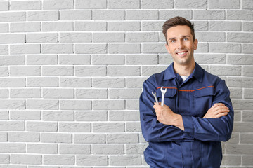 Male car mechanic near brick wall