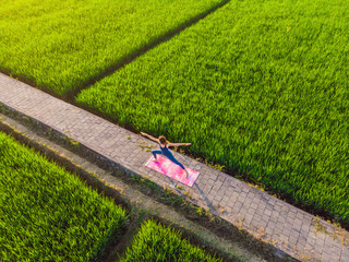 Young woman practice yoga outdoor in rice fields in the morning during wellness retreat in Bali....